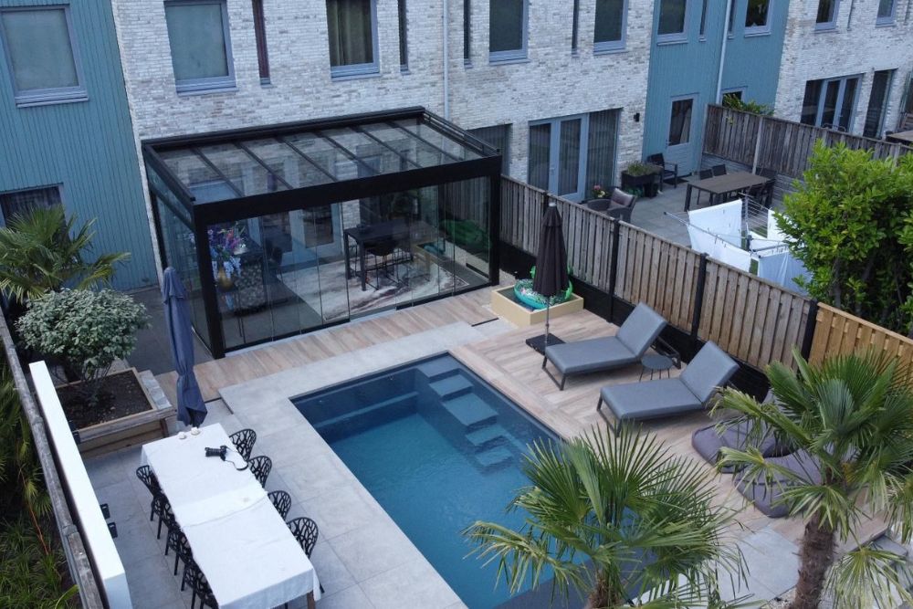 Moderner Wintergarten mit schwarzer Aluminiumkonstruktion, Glasschiebetüren und stilvollem Poolbereich im modernen Außenbereich.