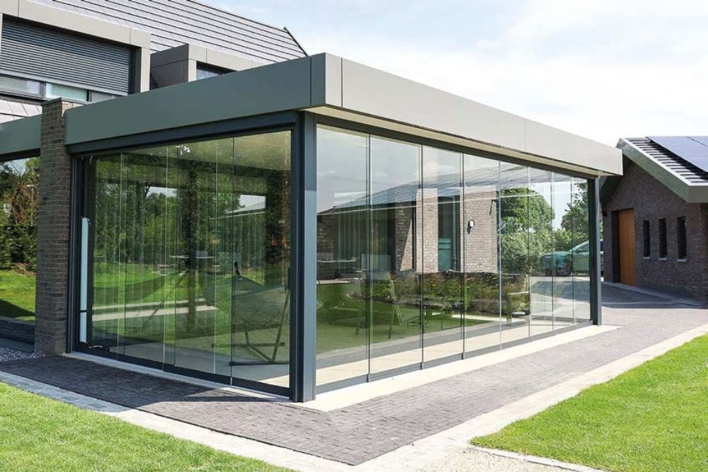 Moderner Wintergarten mit großflächiger Glasfront und hochwertiger Aluminiumkonstruktion in einem stilvollen Außenbereich.