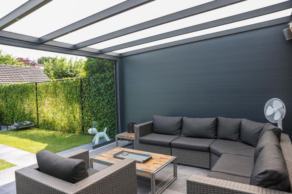 Moderner Outdoor-Lounge-Bereich mit Terrassenüberdachung, Glasschiebetüren und hochwertiger Aluminiumkonstruktion.