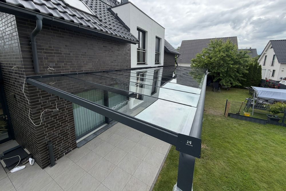 Große Terrassenüberdachung aus anthrazitfarbenem Aluminium mit Glasdach an einem Einfamilienhaus in Lünen