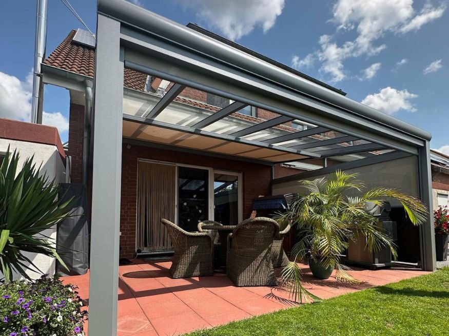 Moderne Terrassenüberdachung aus Aluminium mit integriertem Sonnenschutz und seitlichem Sichtschutz an einem Einfamilienhaus in Dortmund.